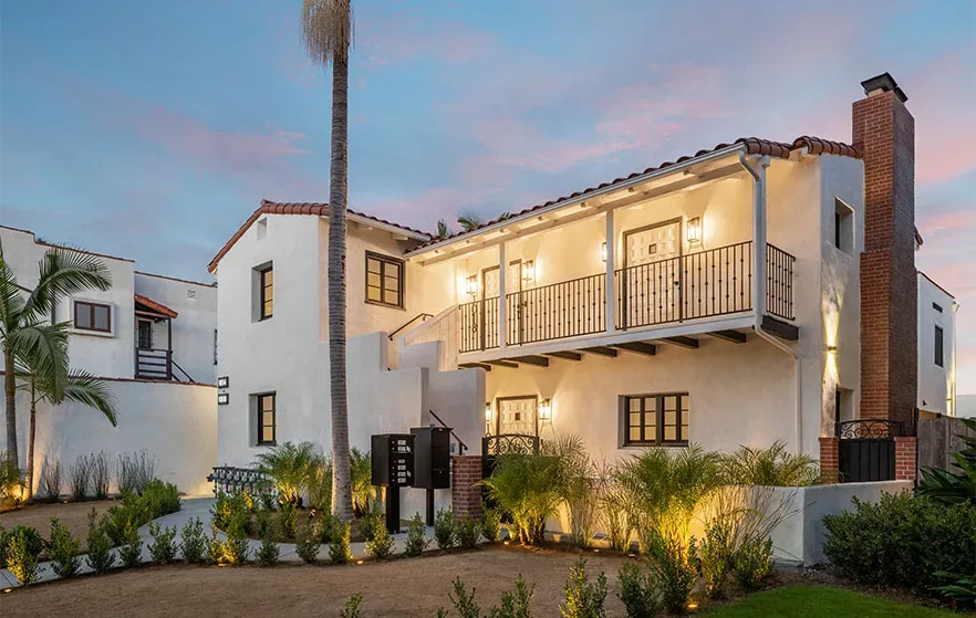 press-testimonials A home with a balcony and palm trees at dusk.
